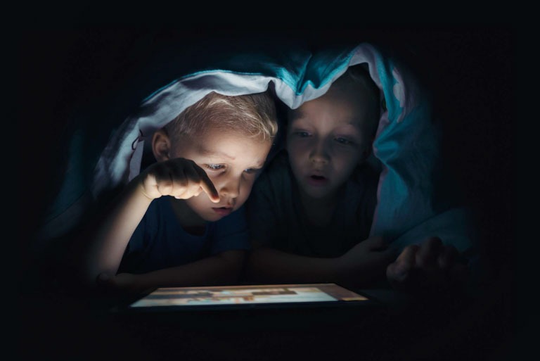 Photo ID: L06. Two kids with tablet computer in a dark room