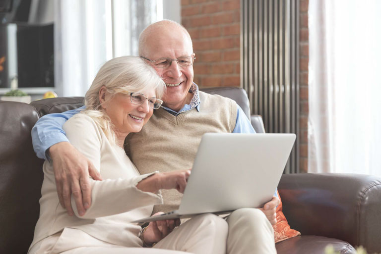 Photo ID: L08. Senior couple browsing the internet together. Retirees using a laptop computer at home