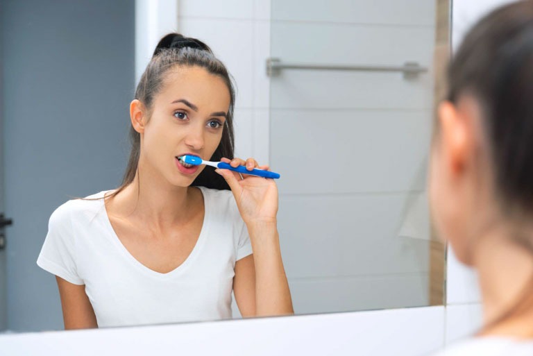 Photo ID: L17. Yooung woman brushing her teeth at mirror. Dental care concept